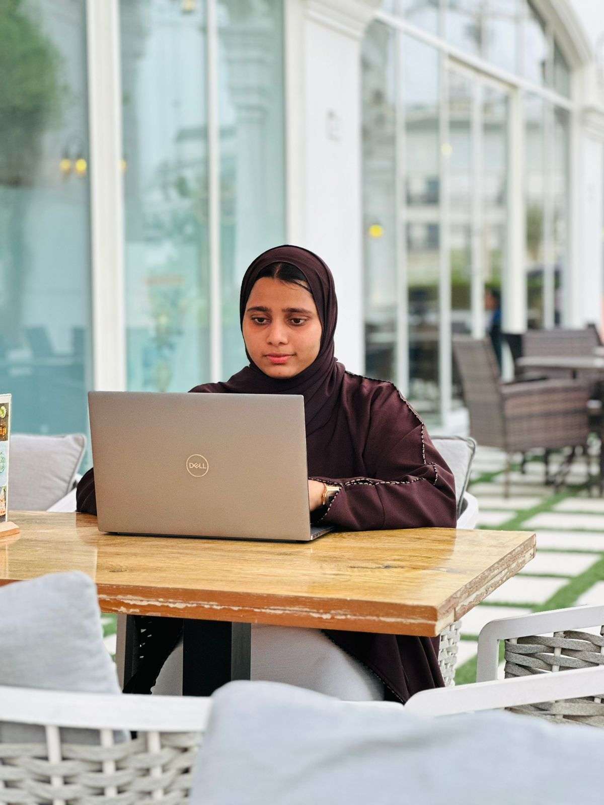 Jusaira Rayees, a freelance digital marketing expert in Dubai, sitting outdoors and working on a laptop, blending her professional expertise with a relaxed, natural environment