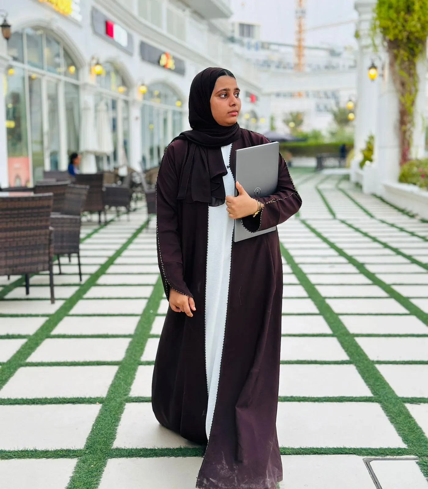 Jusaira Rayees, a freelance digital marketing expert in Dubai, confidently holding a laptop in a professional setting, symbolizing her expertise in SEO and social media marketing.